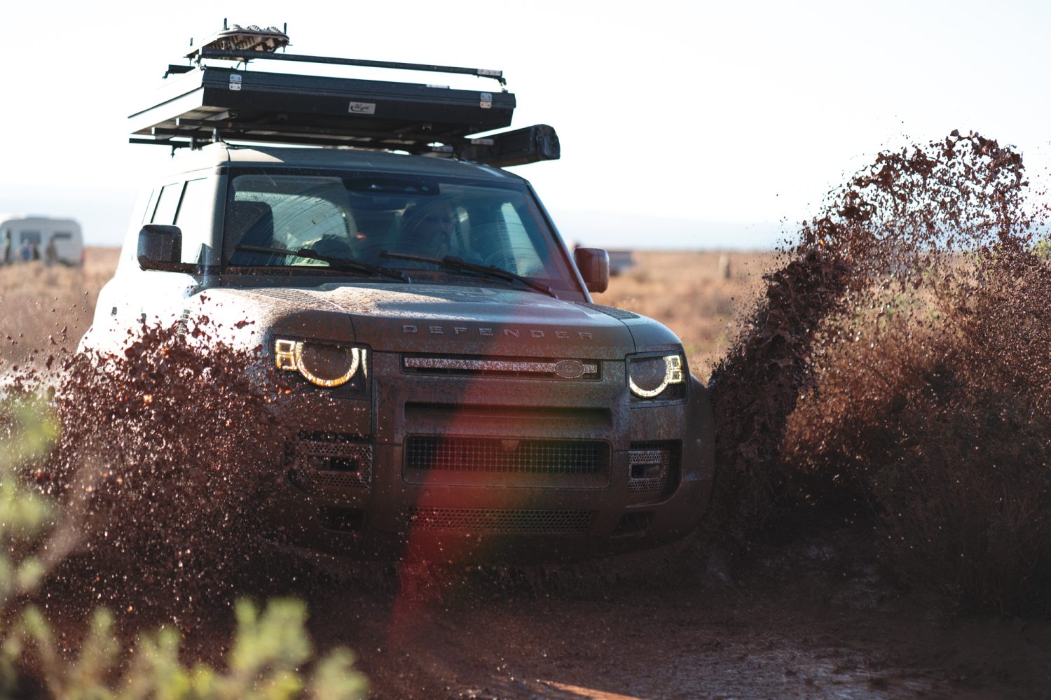 Land Rover Defender driving through mud on overland trip