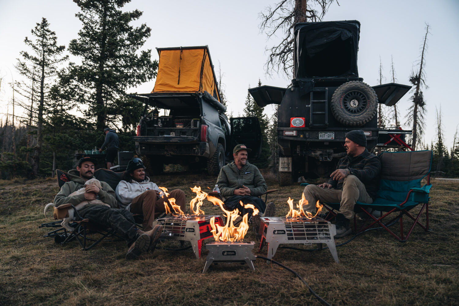 Campers sitting around HOWL Campfires with overland trucks in background