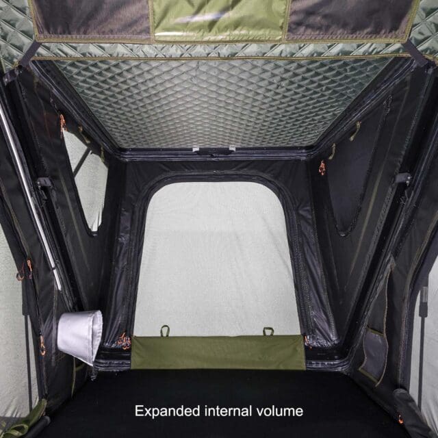Interior view of a spacious tent with mesh windows, quilted ceiling, and a foldable sleeping platform. As featured in Overland News, the caption reads, Expanded internal volume.