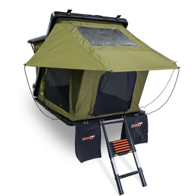 Featured in Overland News, this green rooftop tent has a black base, mesh windows, skylight, and a collapsible ladder. Two black storage bags hang near the ladder, making it ideal for vehicle camping adventures.