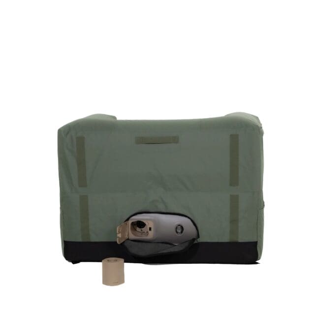 A green and black portable restroom privacy tent, featured in Overland News, with an open flap reveals a tan portable toilet and a toilet paper roll placed on the ground in front.