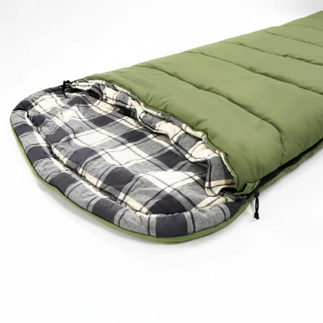 A green sleeping bag with a plaid gray, white, and black interior is partially unzipped and laid out flat on a white surface—perfect for your next adventure featured in Overland News.