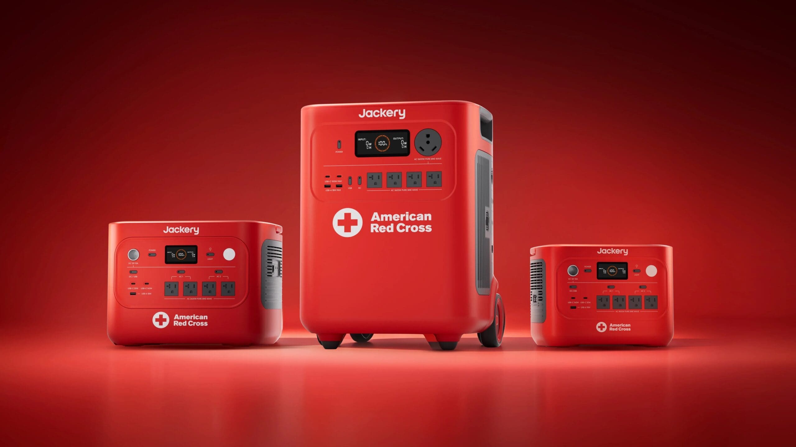 Three red Jackery portable power stations with the American Red Cross logo are displayed on a red background, featured in Overland News, showcasing multiple power outlets and USB ports on their front panels.