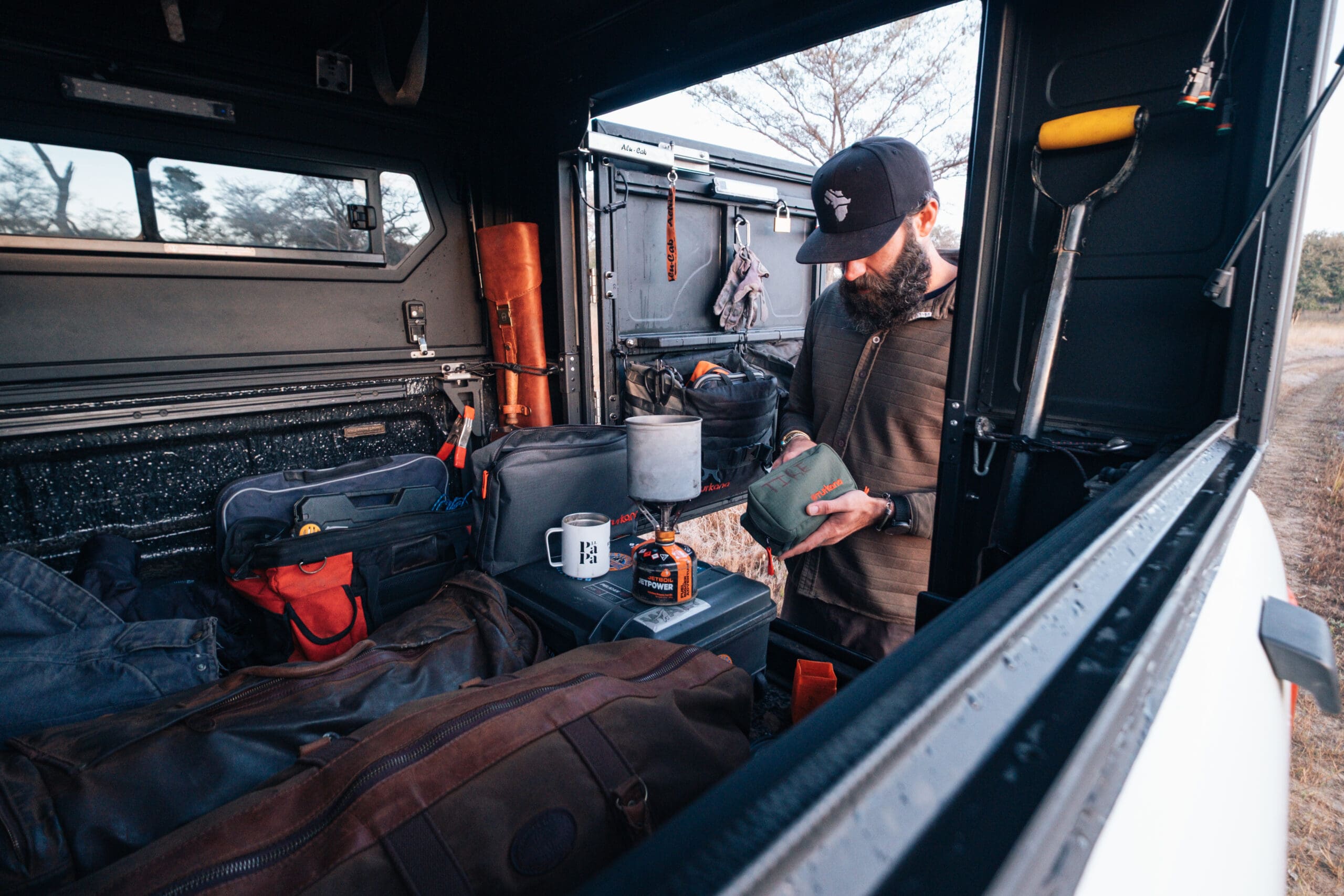 man standing at rear of truck camper shell with hatch opened