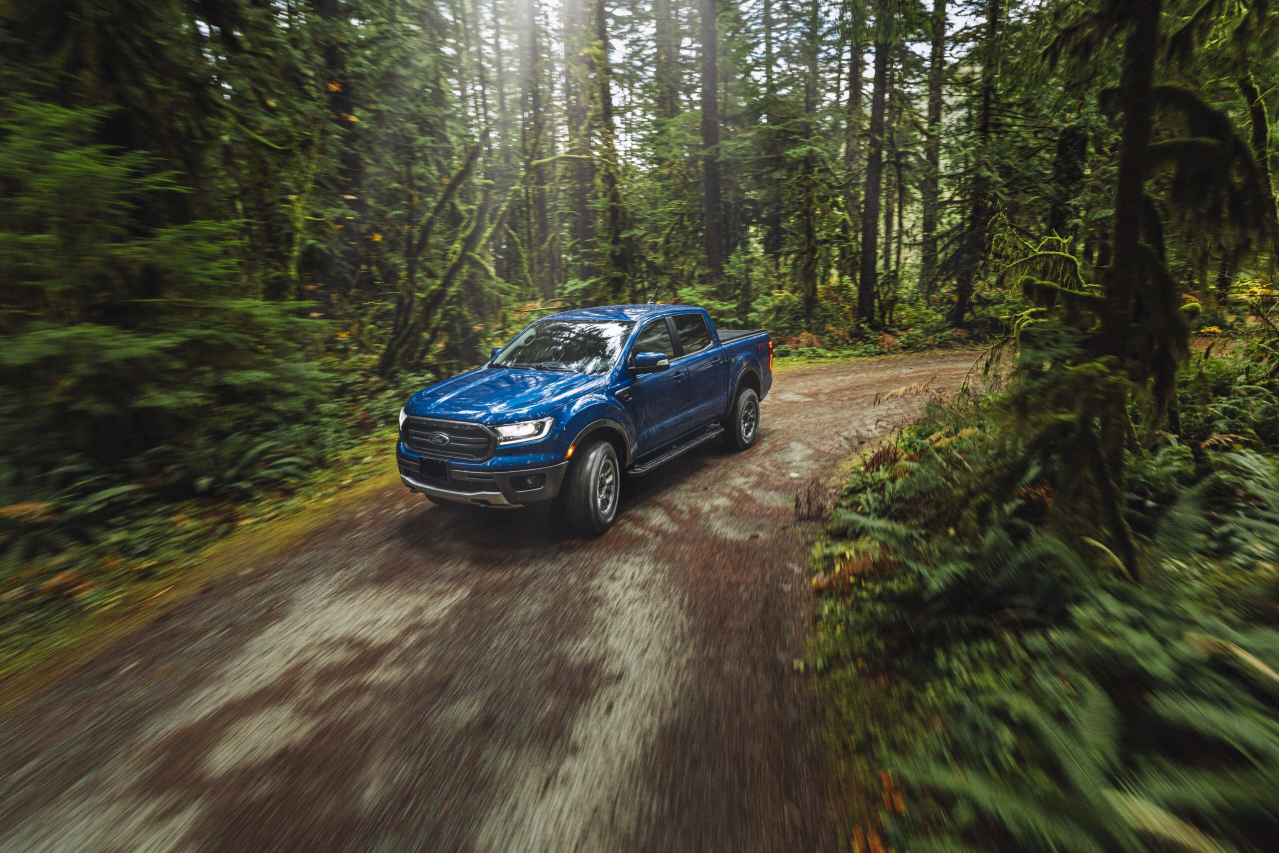 blue truck driving through a forest
