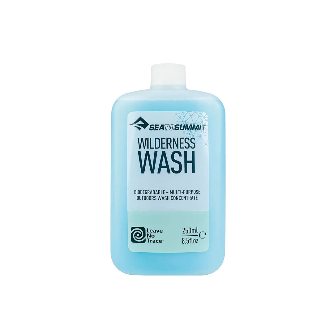 A blue 250ml bottle of Sea to Summit Wilderness Wash, labeled as biodegradable, multi-purpose outdoors wash concentrate, with a white cap and eco-friendly Leave No Trace logo—perfect for Laundry at Camp and other camp laundry needs.