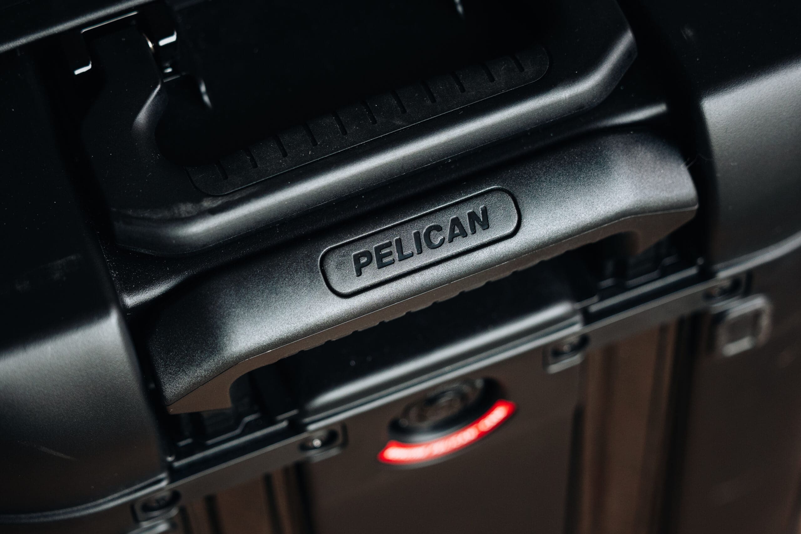 Close-up of a black hard case with the brand name PELICAN embossed on the handle, showcasing the field-tested durability of Pelican ATX.