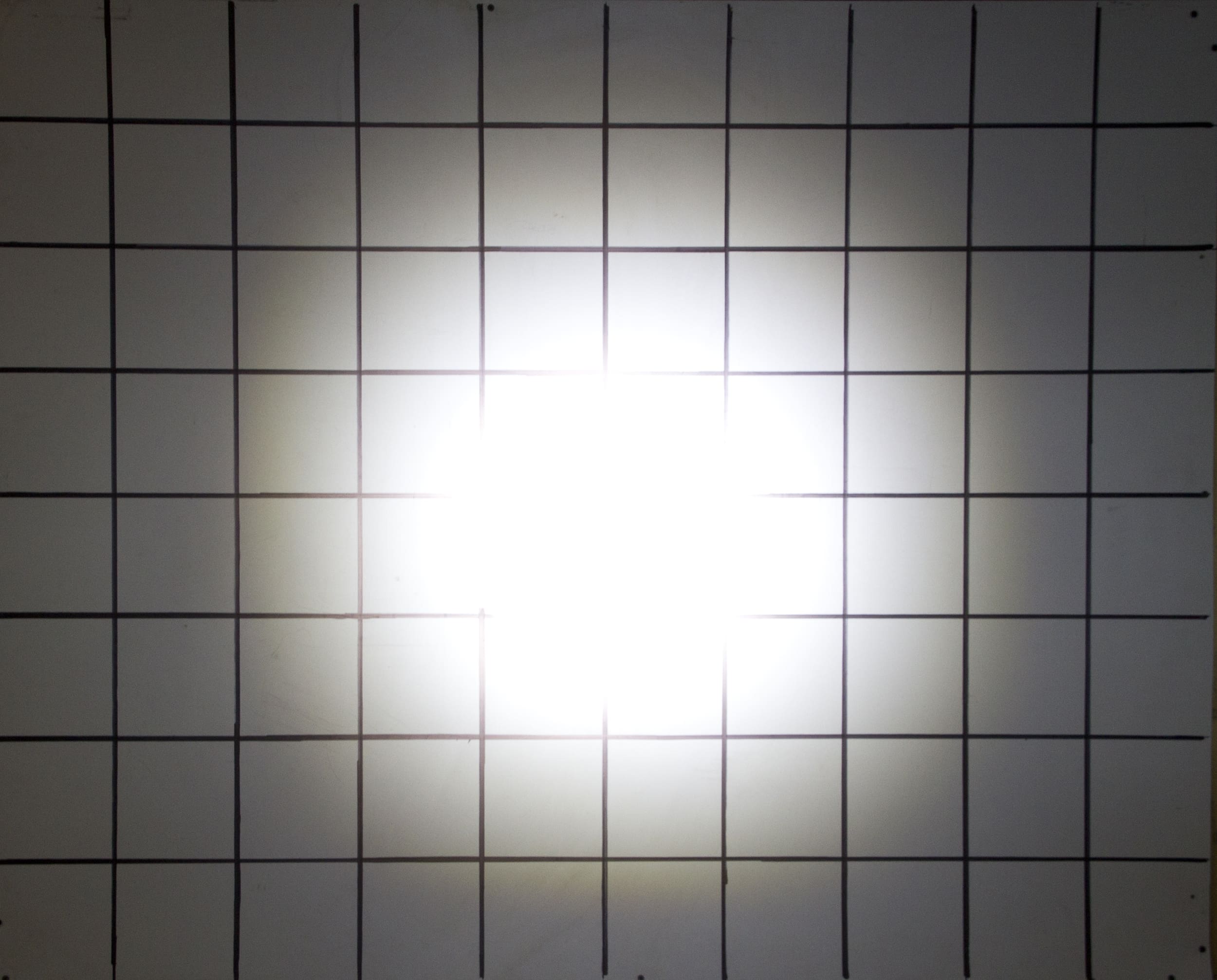 A grid of black lines forms squares on a white surface, with a bright white light glowing intensely at the center, reminiscent of powerful driving lights, creating a radiant effect and slight glare.