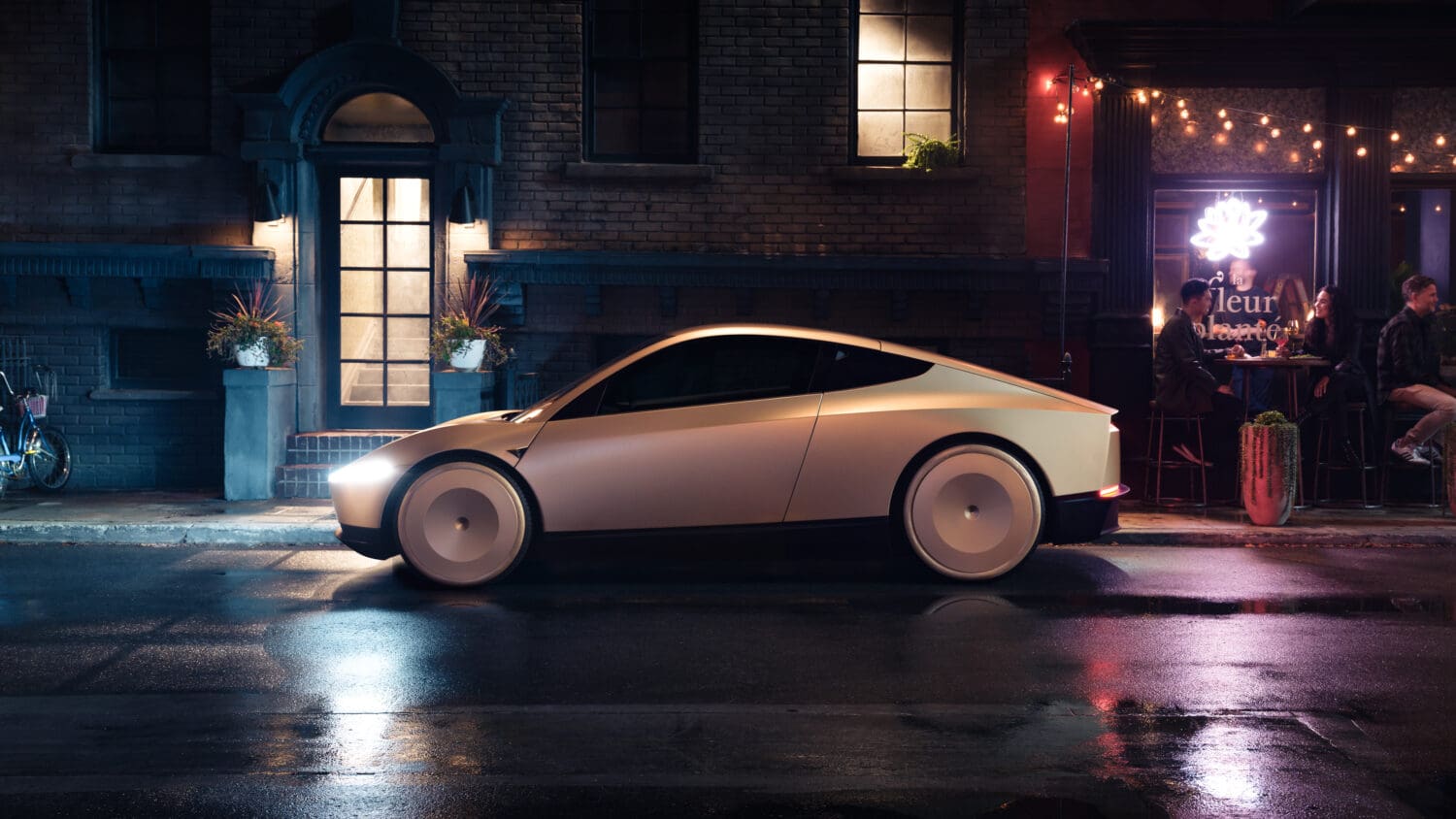A sleek, modern electric car—equipped for autonomous overlanding—is parked on a wet city street at night in front of lit buildings and a small restaurant where people are seated inside.