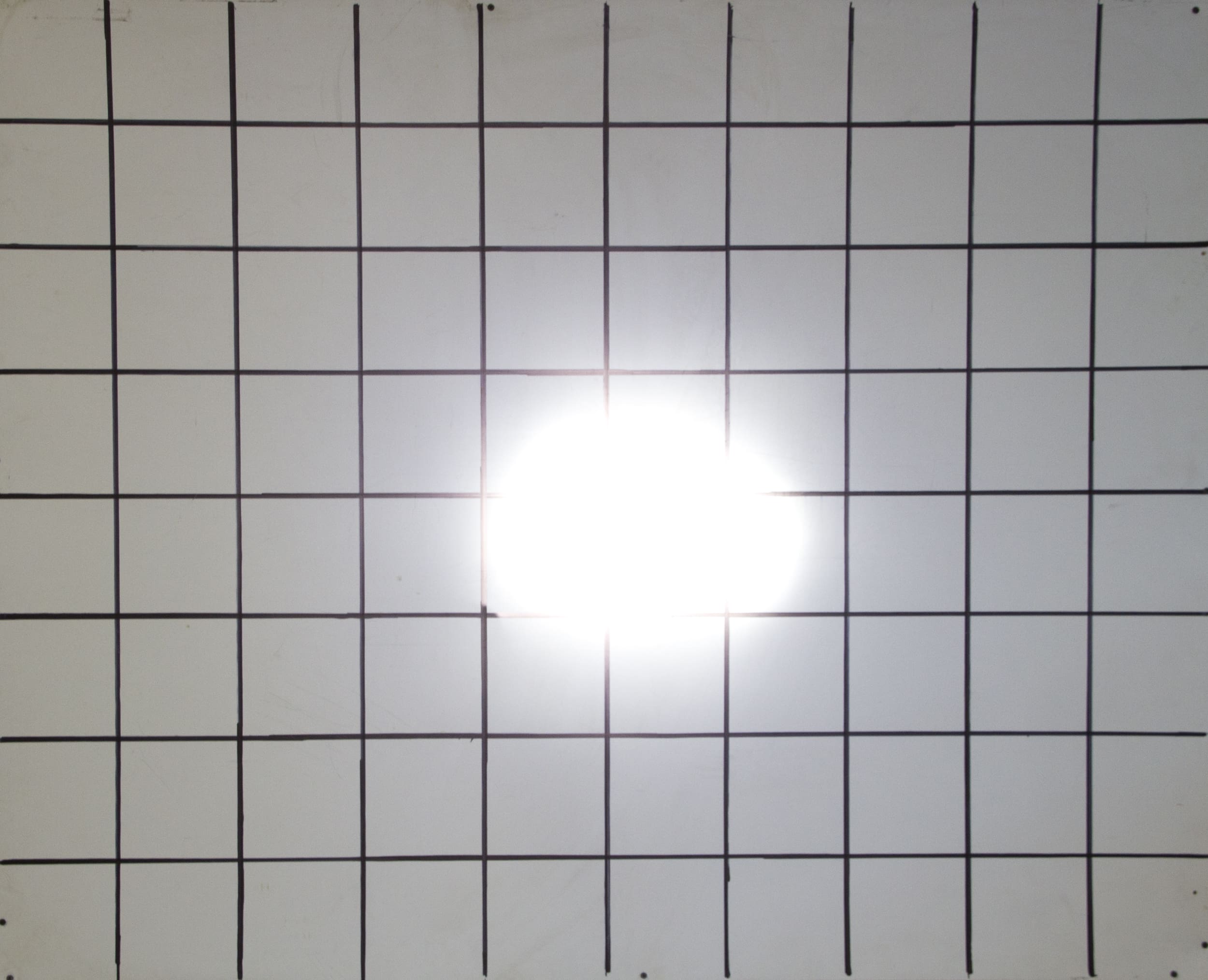 A white grid on a board with a bright, blurry light spot in the center—reminiscent of intense driving lights—partially obscuring some of the grid lines.