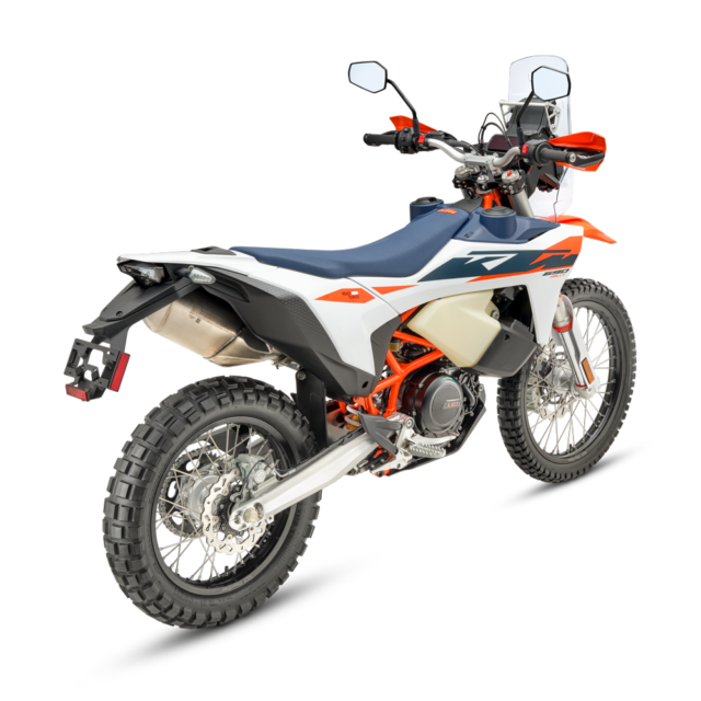 A rear-side view of the 2027 KTM 690 Rally off-road motorcycle with knobby tires, orange and blue accents, a high mudguard, and visible engine and suspension components, set against a plain white background.