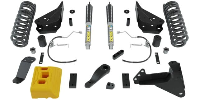 A Jeep suspension lift kit with coil springs, shocks, spacers, brackets, hardware, and a yellow bump stop block arranged neatly on a white background—perfect for readers of Overland News seeking reliable off-road upgrades.