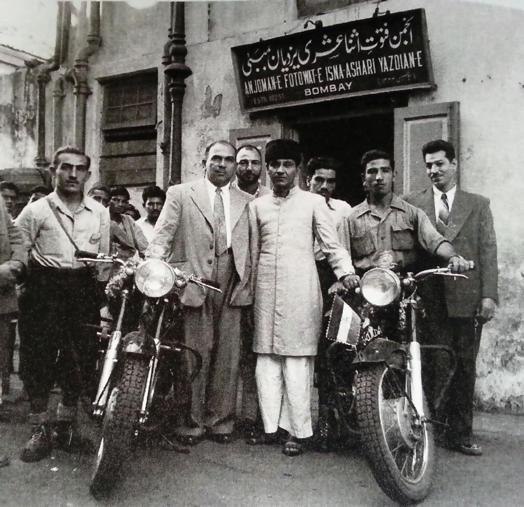 A black-and-white photo shows the Omidvar brothers and others posing with two motorcycles in front of a building with a Persian and English sign mentioning Bombay. The men wear suits, traditional attire, and casual shirts.