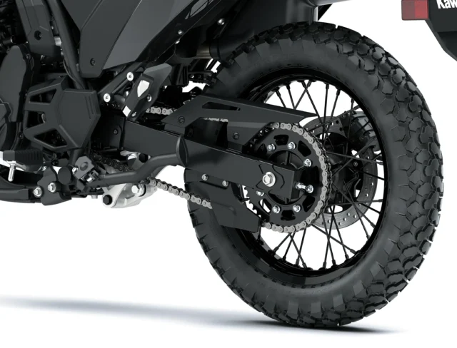 Close-up of a Kawasaki KLR650 rear wheel, highlighting the chain drive, sprocket, and knobby tire.