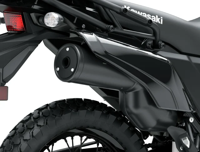 Close-up of a Kawasaki KLR650 rear section, highlighting the black exhaust pipe, taillight, turn signal, and knobby rear tire.