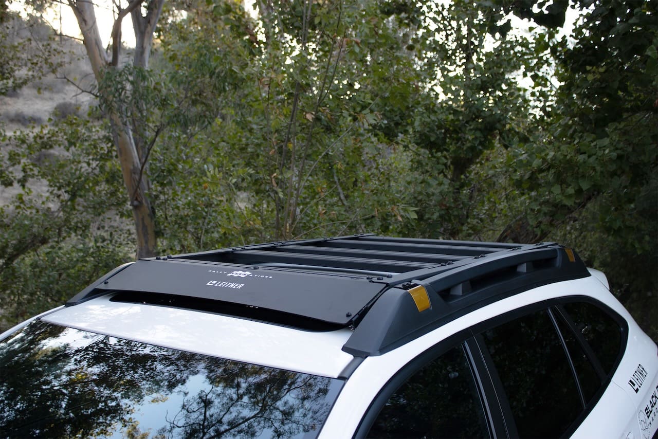 A black Leitner Designs roof rack mounted on a white vehicle.