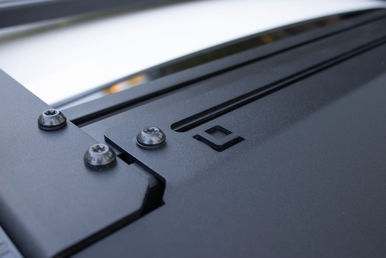 Close-up of a black metal Leitner Designs vehicle roof rack system with exposed Torx screws.