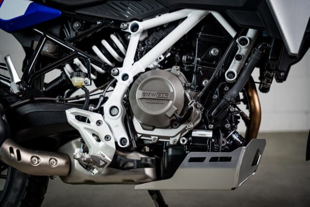 Close-up of a BMW Motorrad engine with a white trellis frame and a silver skid plate.