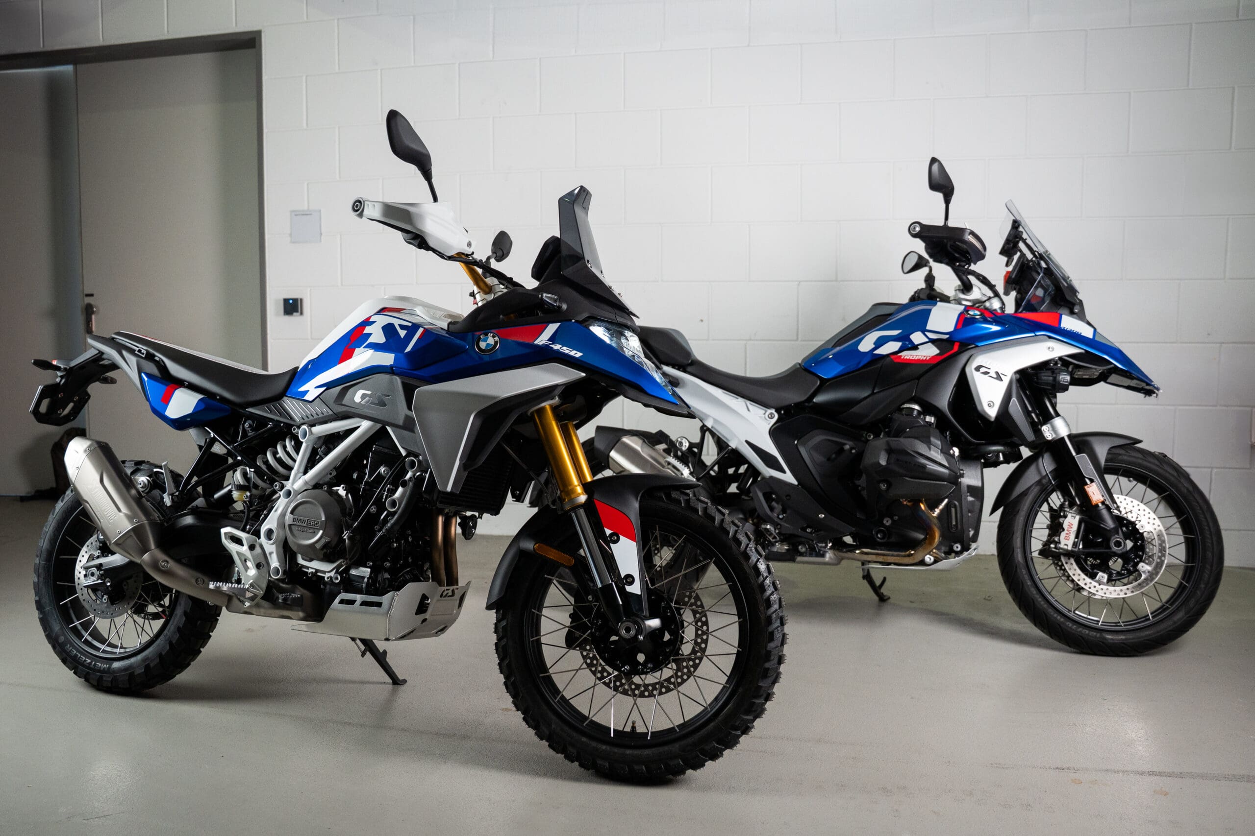 Two BMW Motorrad GS adventure motorcycles parked side-by-side in a garage.