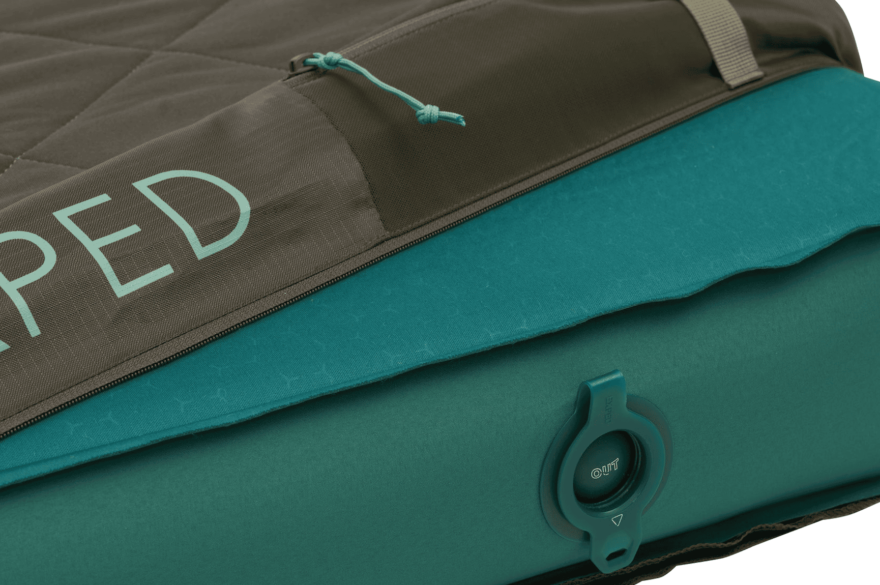 Close-up of a teal Exped sleeping pad for Overland News, showing an inflation valve labeled OUT and a partial view of a quilted brown cover.