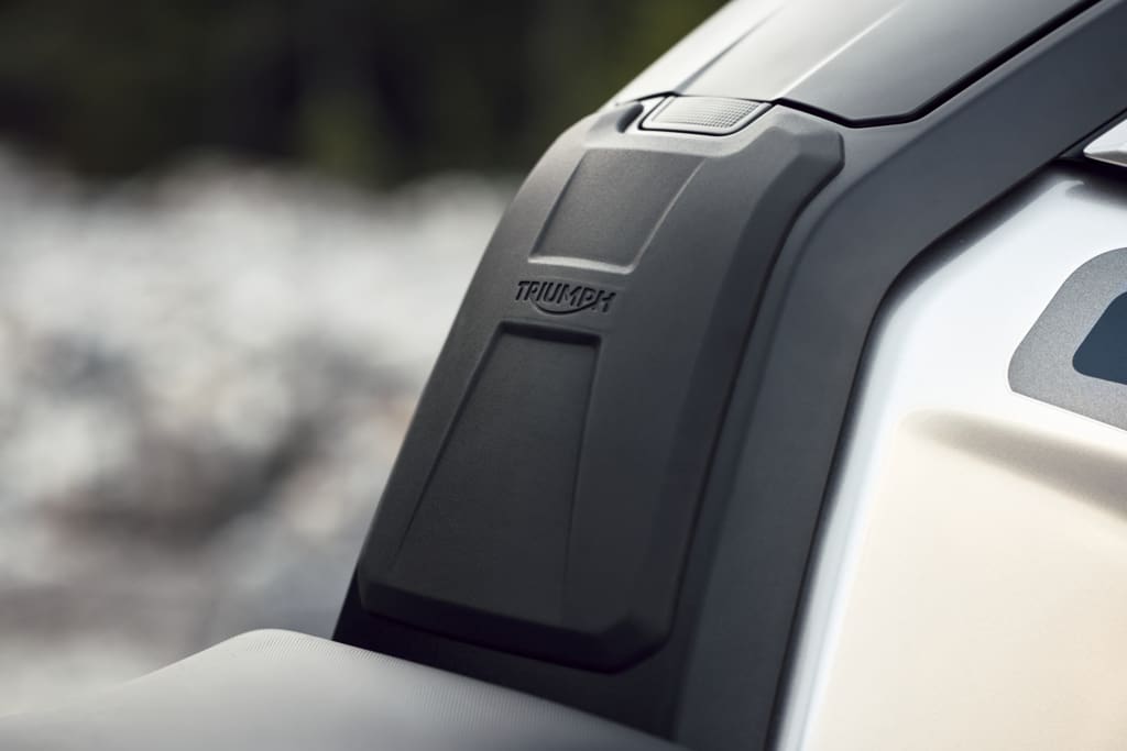 Close-up of a black Triumph Tiger 1200 fuel tank cover featuring the embossed Triumph logo.