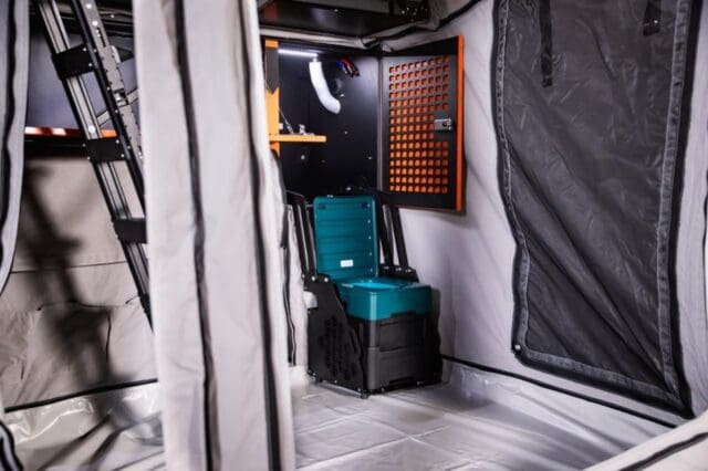 Interior of a Patriot Campers tent featuring a collapsible toilet unit and a wall-mounted storage cabinet.